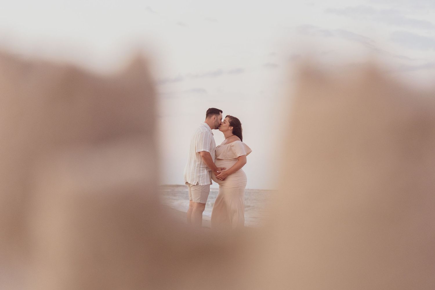Dreamy soft-focus portrait of couple embracing during maternity photoshoot.