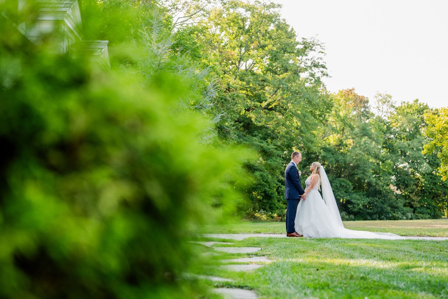 Wedding couple walking through lush green garden setting on their special day.