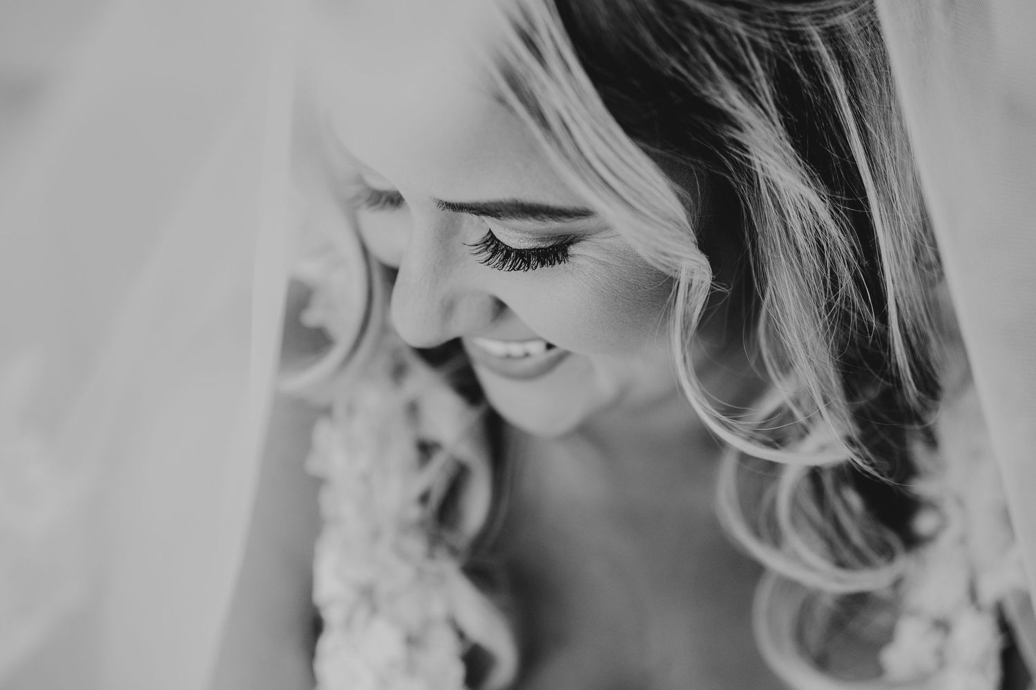 Close-up artistic black and white portrait showing delicate bridal makeup and veil details.