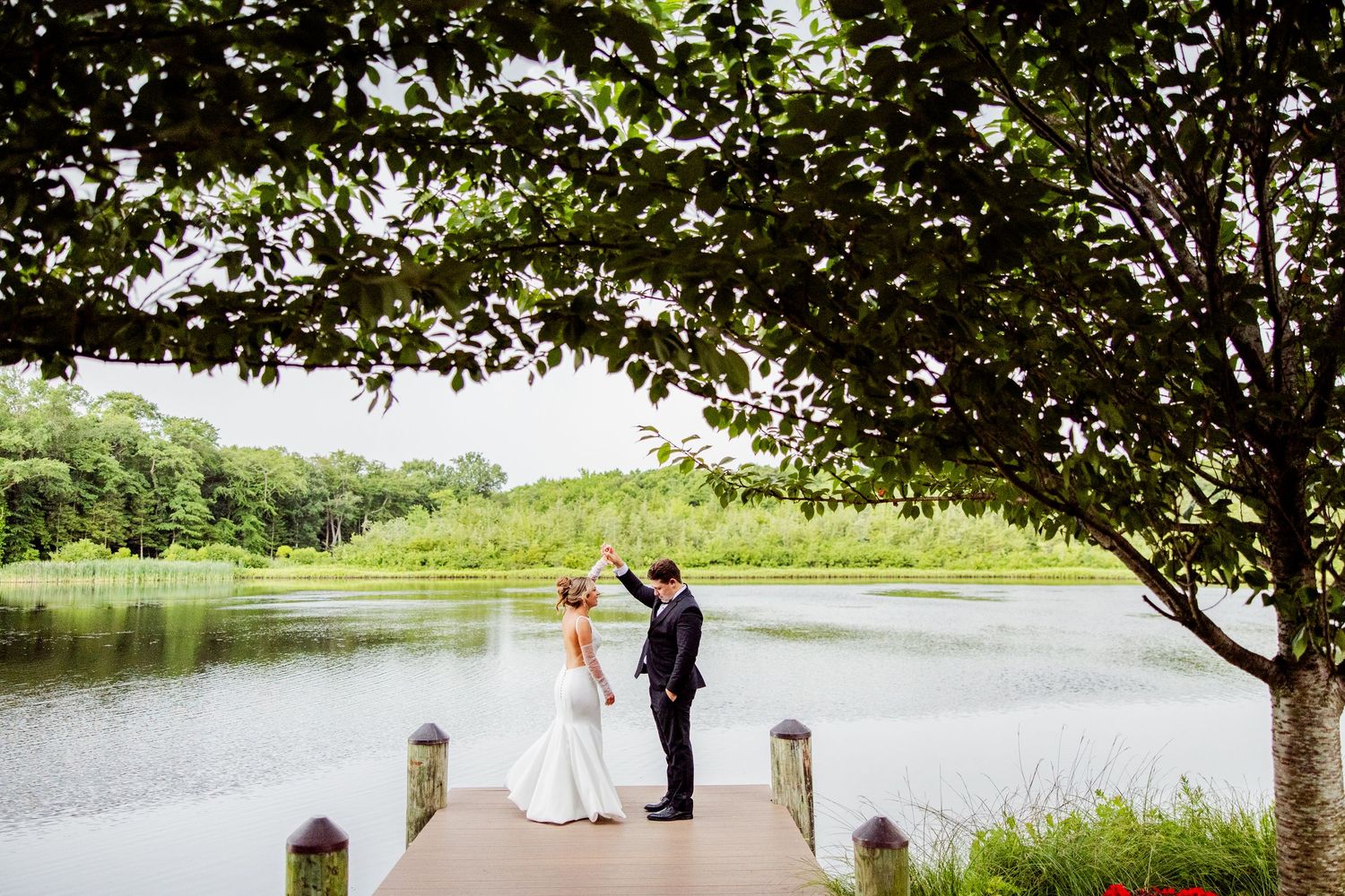 Wedding couple poses along a scenic lakeside path with overhanging trees. The Mill New Jersey
