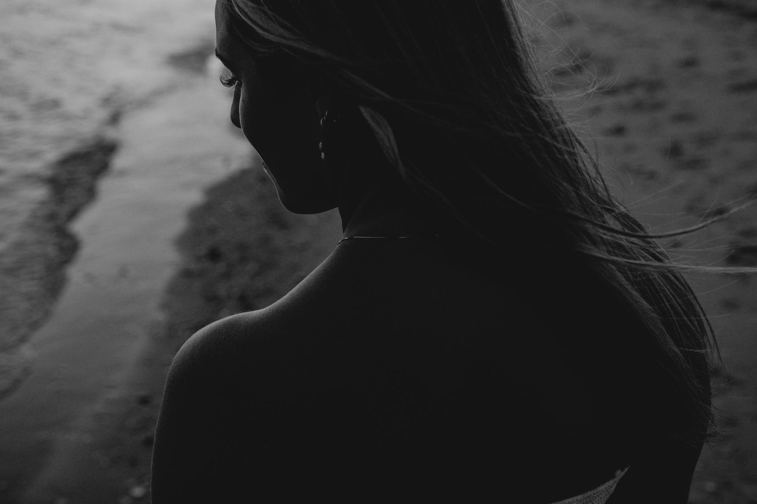 Black and white portrait of a woman with long hair on a beach.