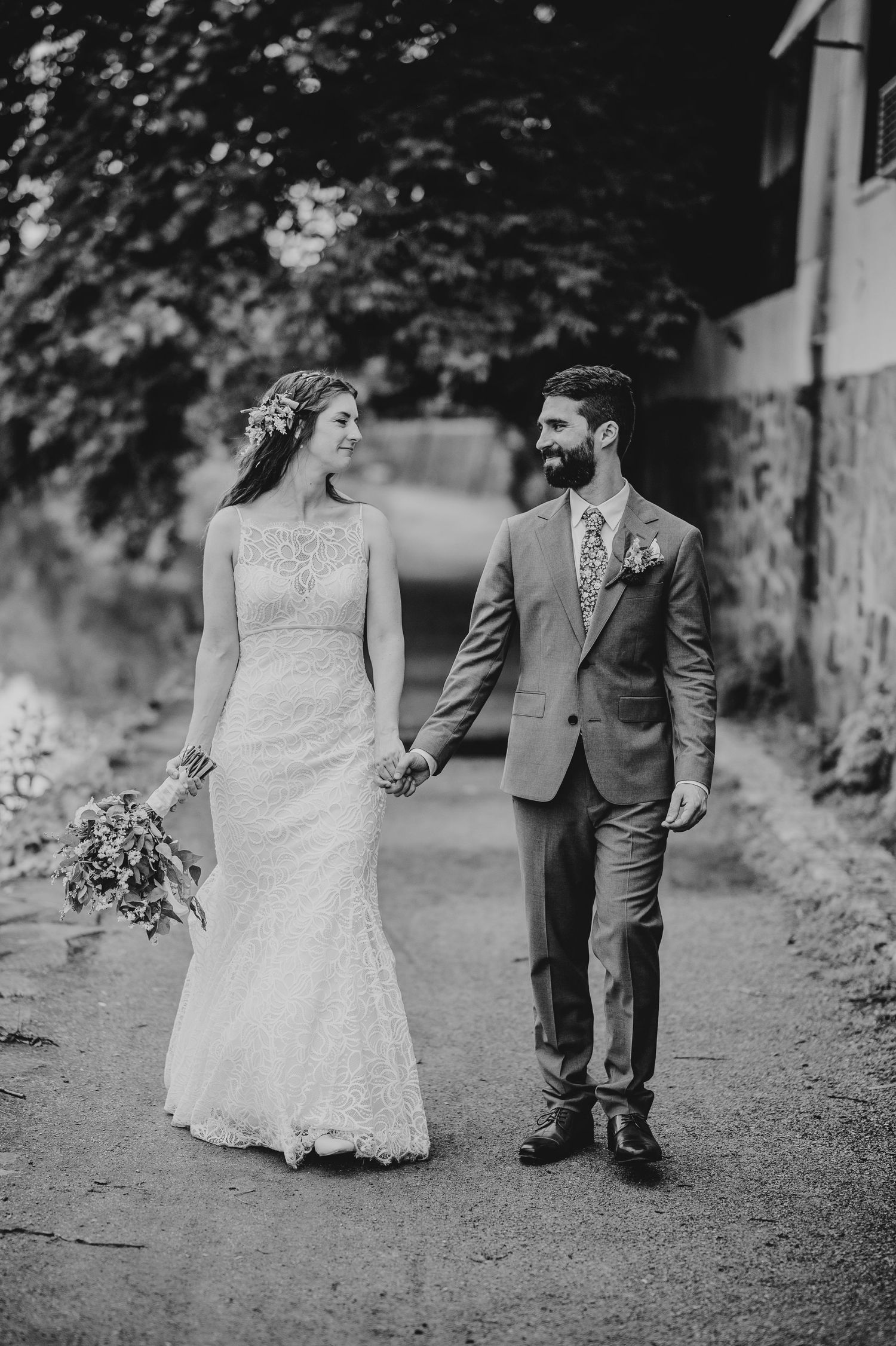Black and white wedding photos of a couple walking together on a tree-lined path.
