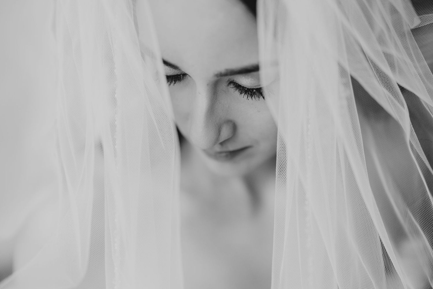 Ethereal bridal portrait through delicate white veil.