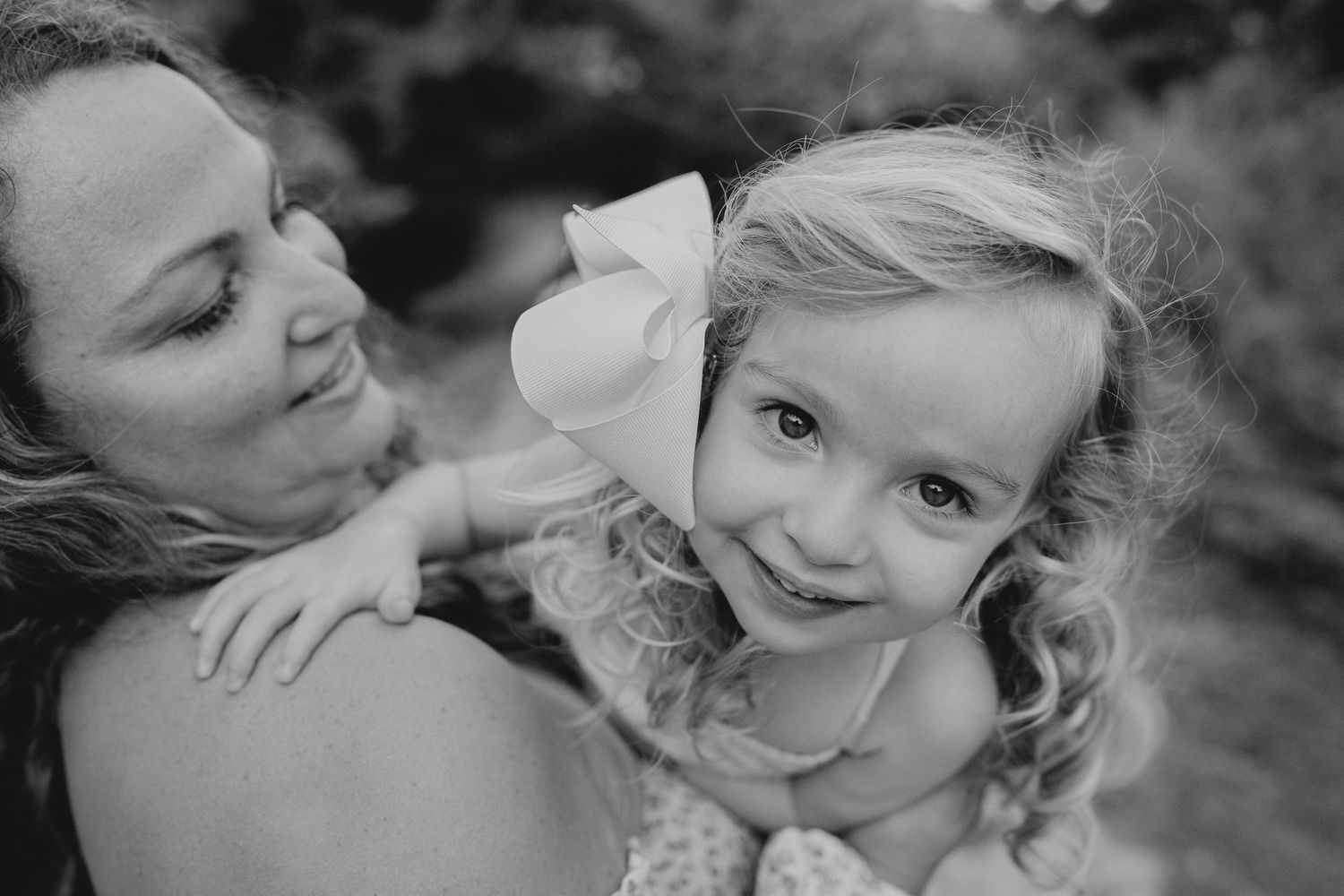 Black and white close-up portrait showing tender affection and connection in natural outdoor setting.