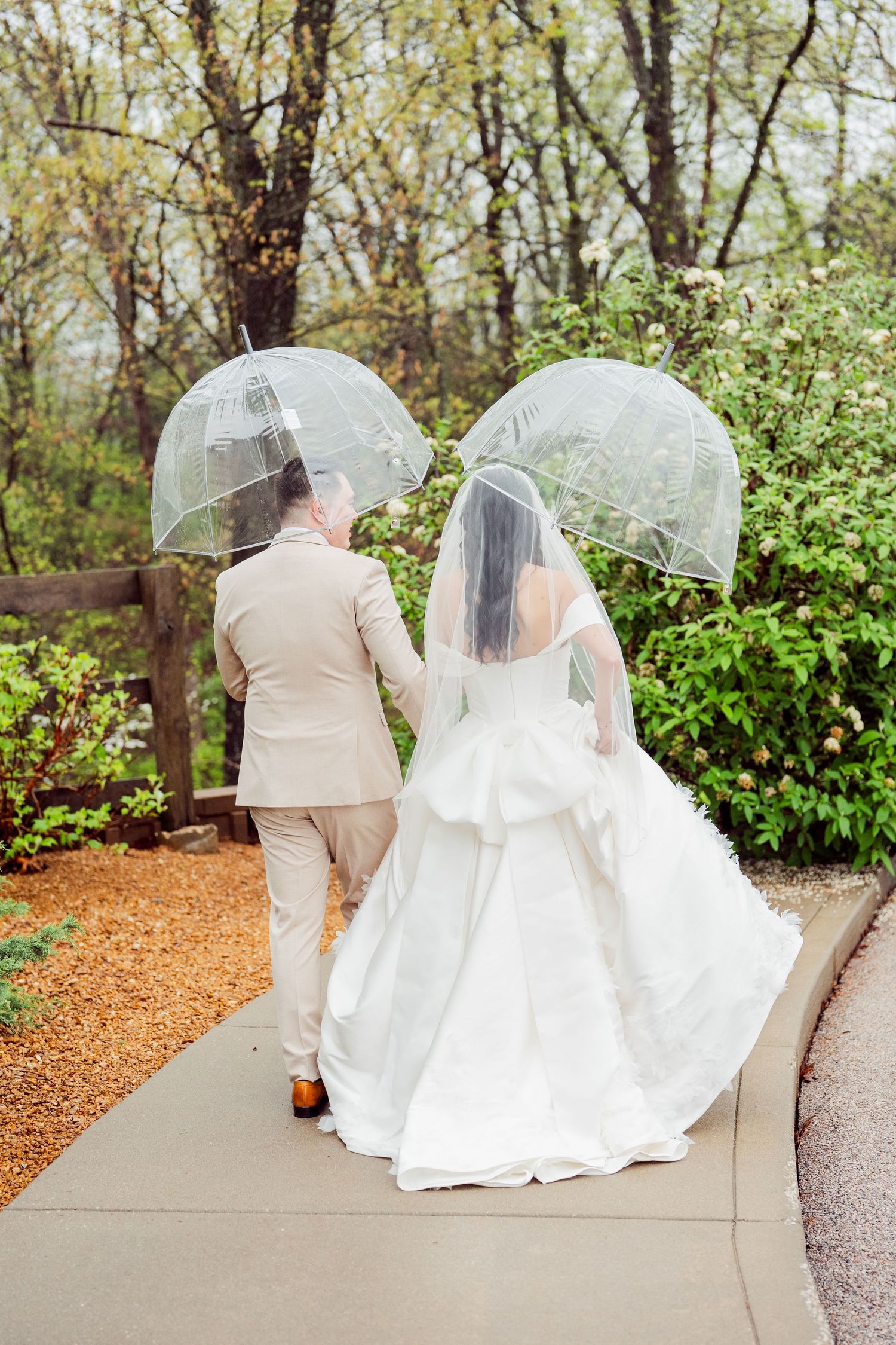 Wedding couple sits together on garden path surrounded by spring foliage.