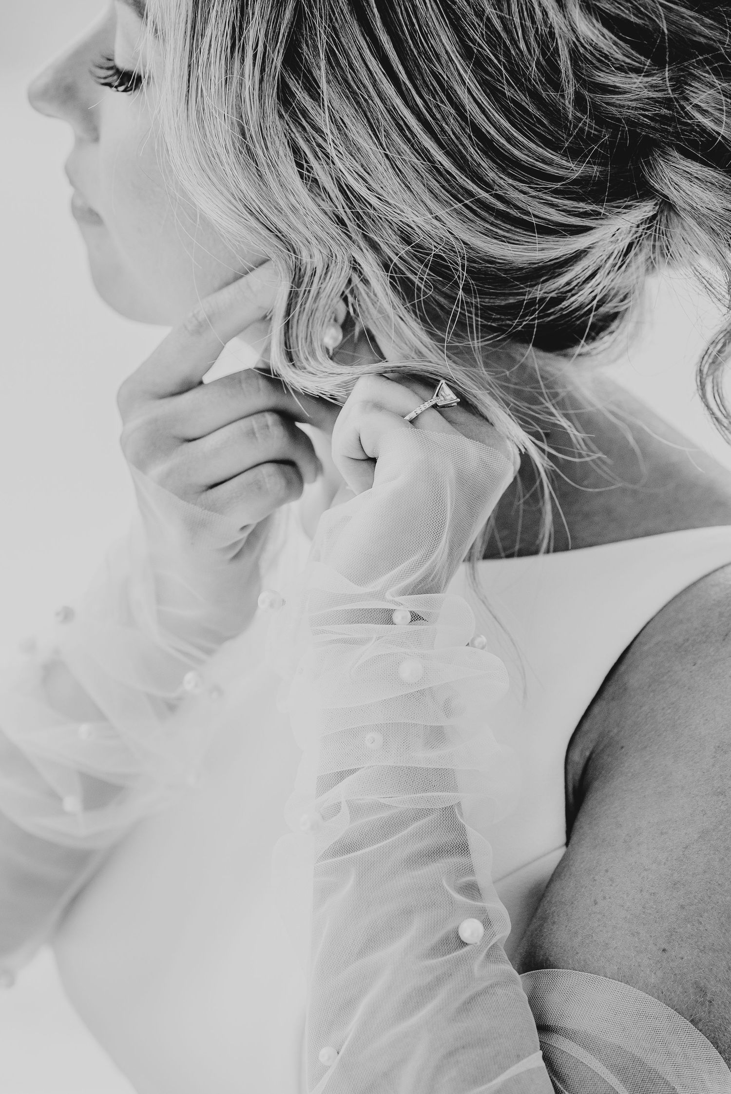 Artistic black and white profile portrait showing delicate details of bridal hair and dress.
