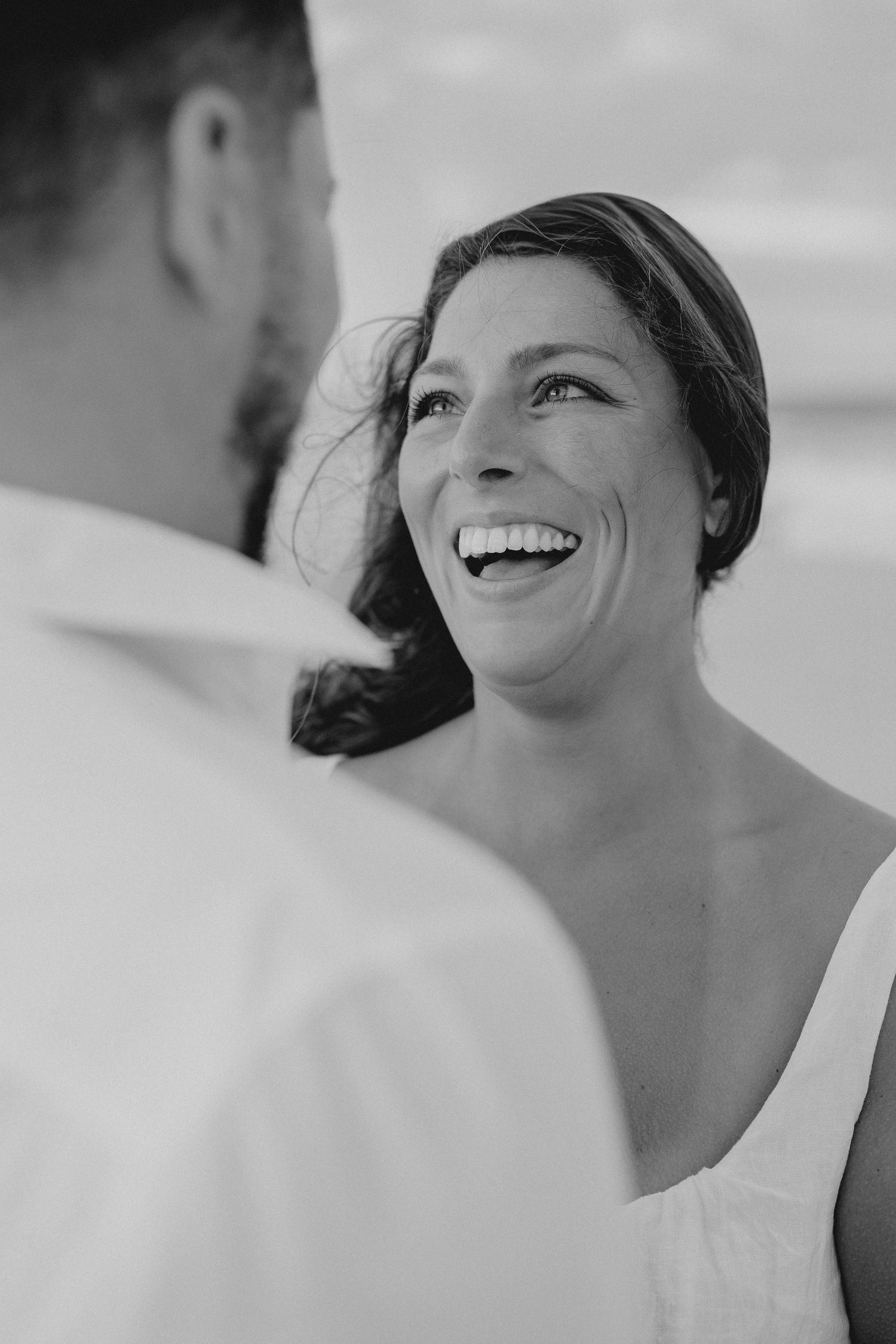 Black and white portraits showing natural laughter and joy during a beach photoshoot.