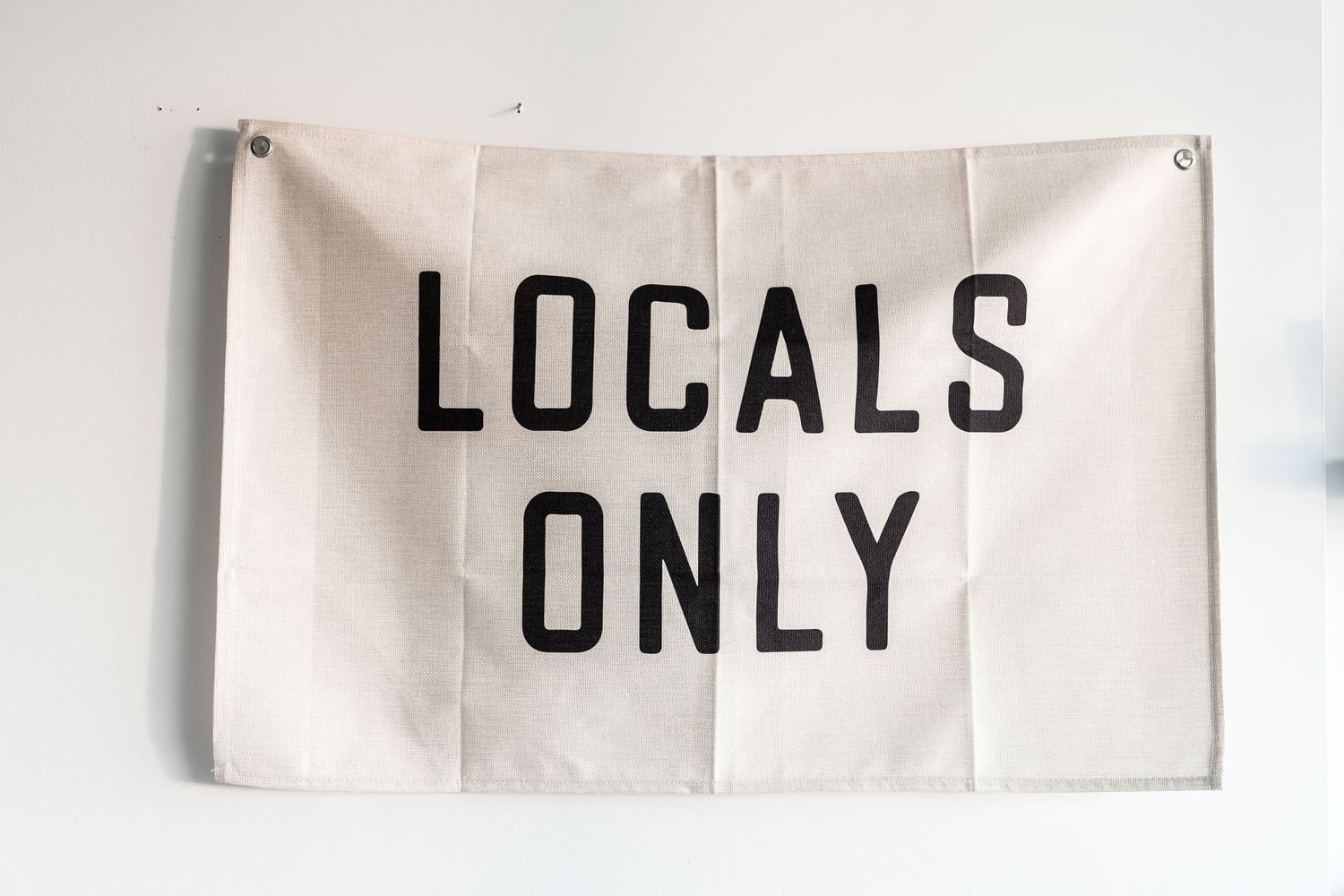 A series of white signs mounted on a wall displaying text fragments including 'LOCALS' and 'ONLY'.