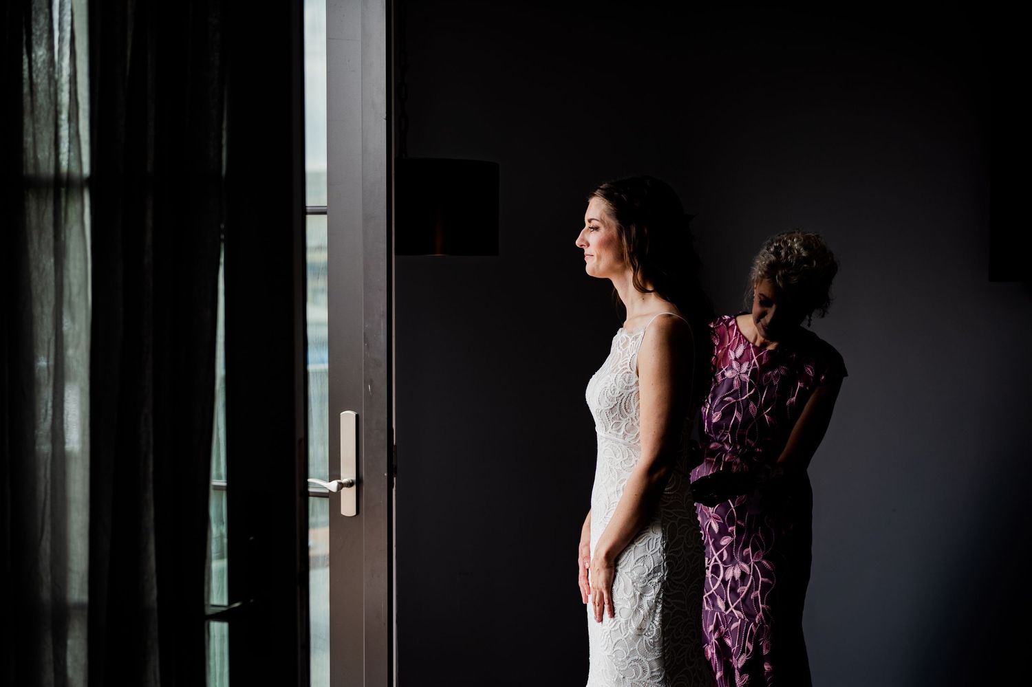 Dramatic indoor wedding preparation photos against a dark wall.