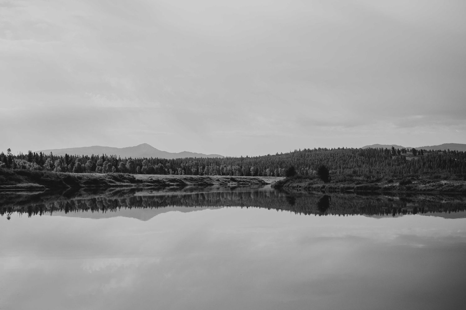 Black and white panoramic landscape of mountains and lakes in Grand Teton National Park with dramatic cloudy sky.
