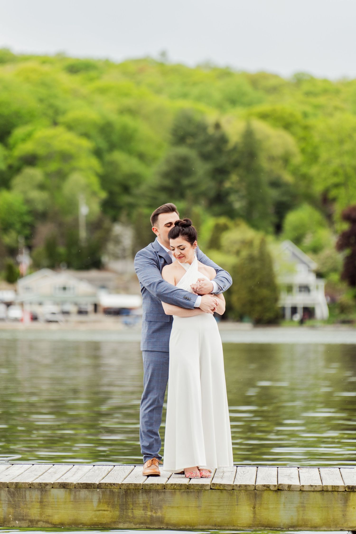 A couple shares an intimate moment on a wooden dock by the lake.