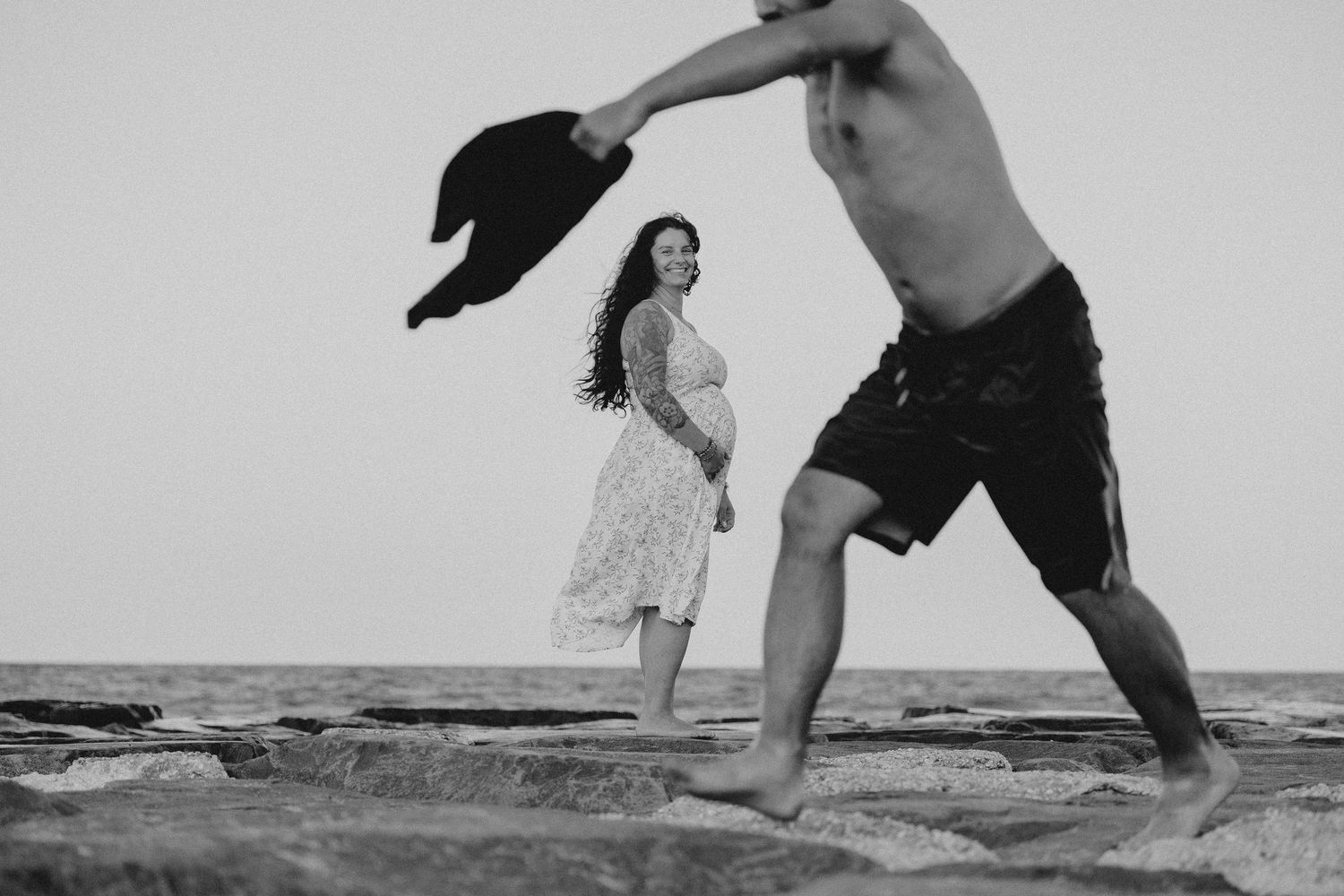 A series of black and white photos showing people splashing and playing in ocean waves at the beach.
