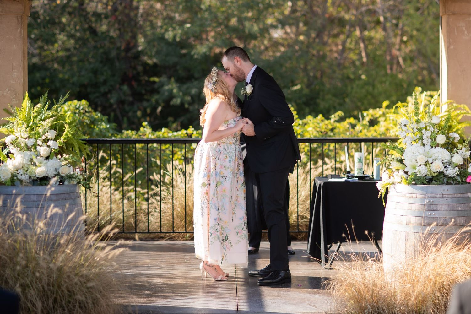 A couple shares an intimate moment on an outdoor terrace surrounded by flowers and natural light.