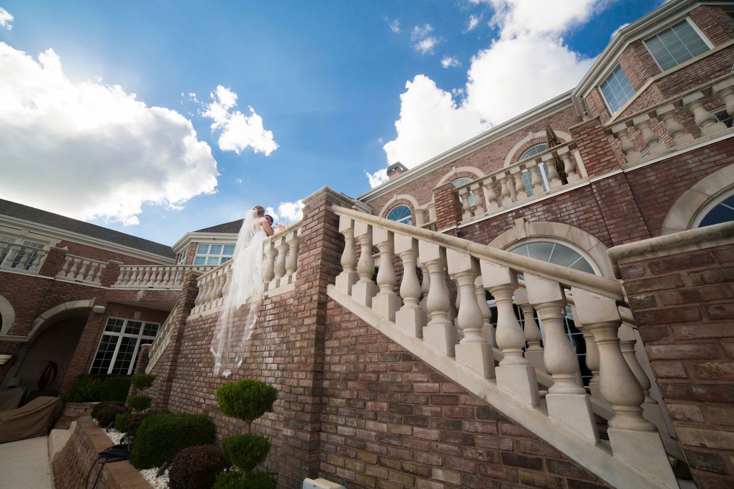 Stone balustrade and architecture of elegant wedding venue against bright blue sky.