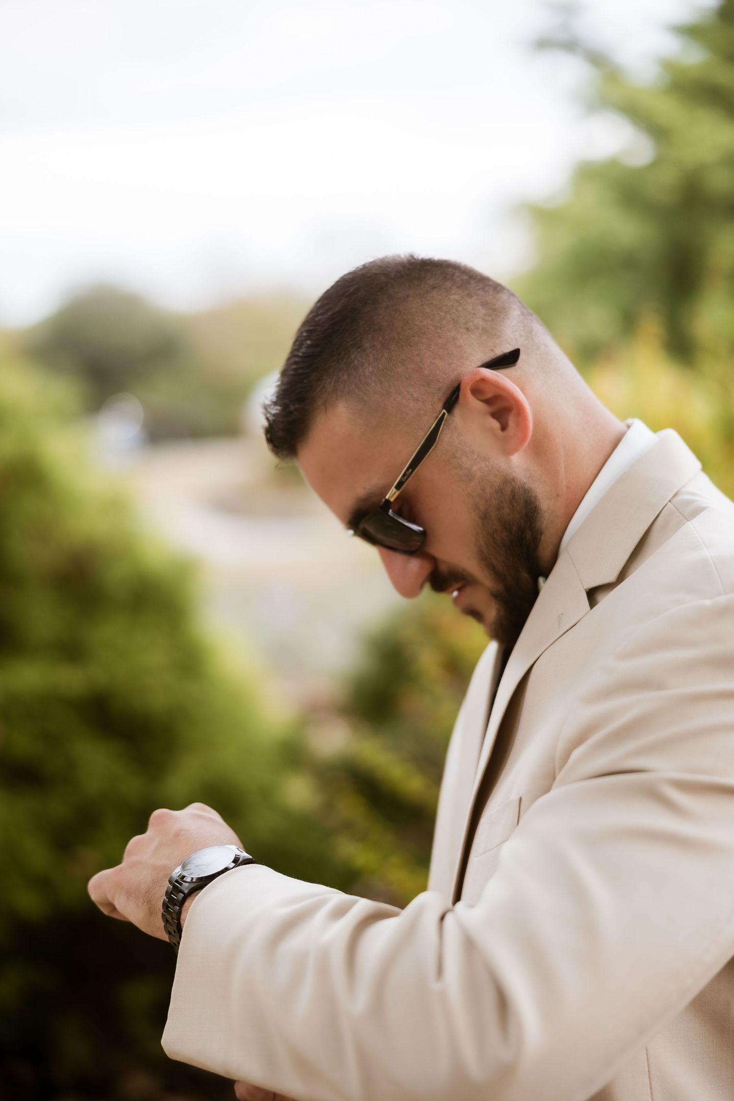 Emotional groom in white suit jacket wipes tears during first look wedding moment.