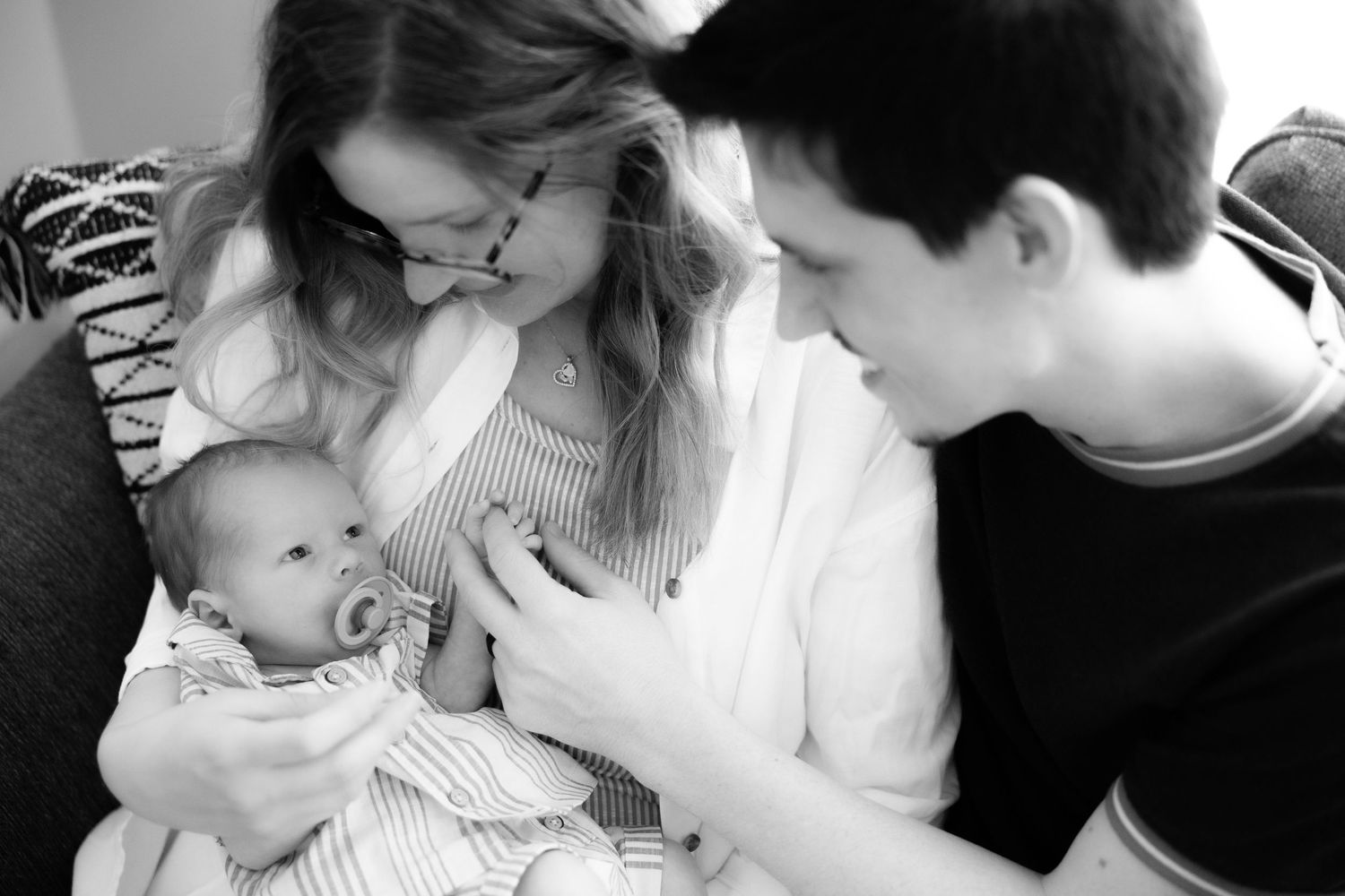 Black and white lifestyle photos capturing intimate family moments indoors.