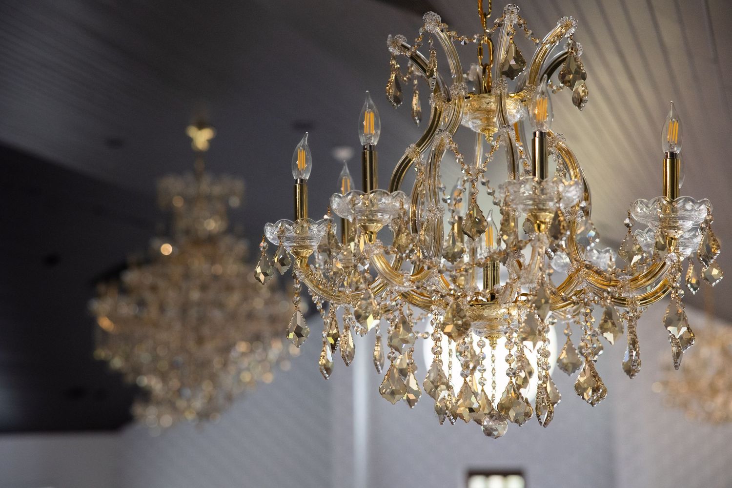 Elegant crystal chandelier with golden accents and multiple tiers sparkles in warm lighting.