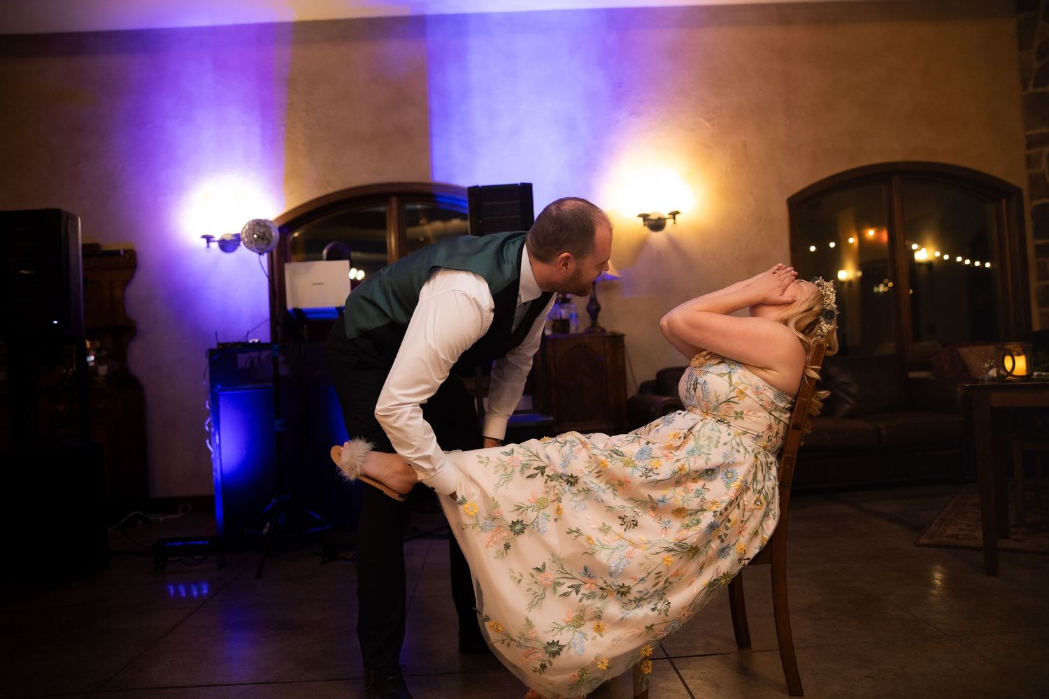 Wedding couple performs a dramatic dance dip move under purple and amber lighting at their reception.