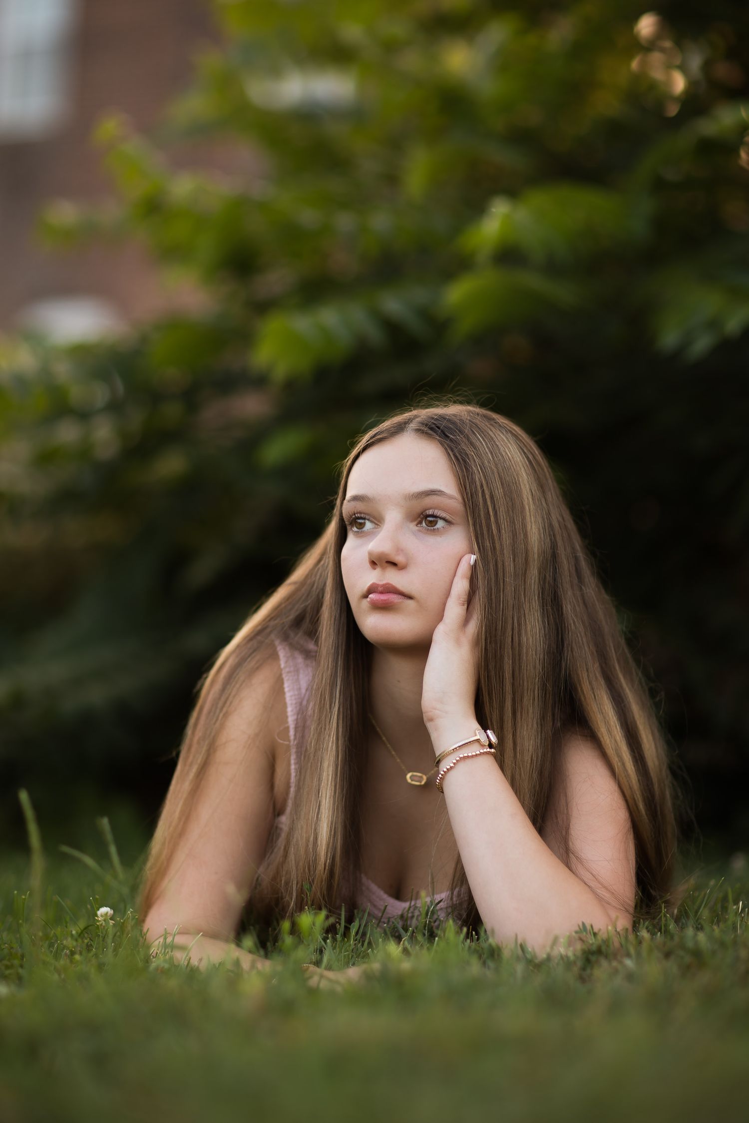 Outdoor portrait in grass with soft natural lighting and brick building background.