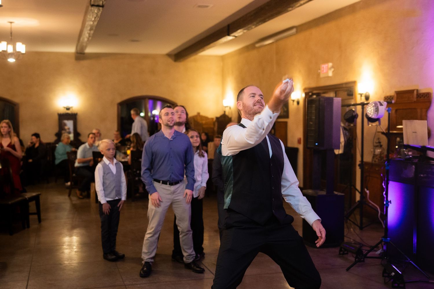 Guests enjoying themselves on the dance floor at an indoor wedding reception.