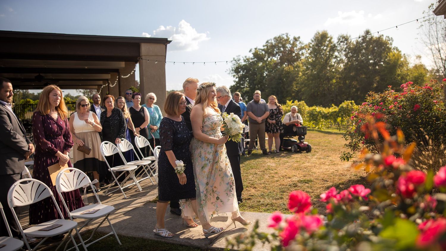 Guests seated in white chairs at an outdoor wedding ceremony with a scenic natural backdrop.