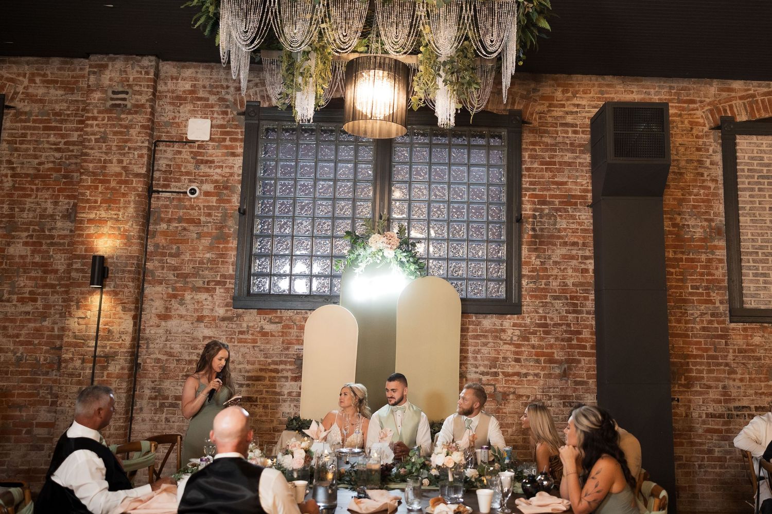 Wedding reception space featuring rustic brick walls and hanging pendant lights.