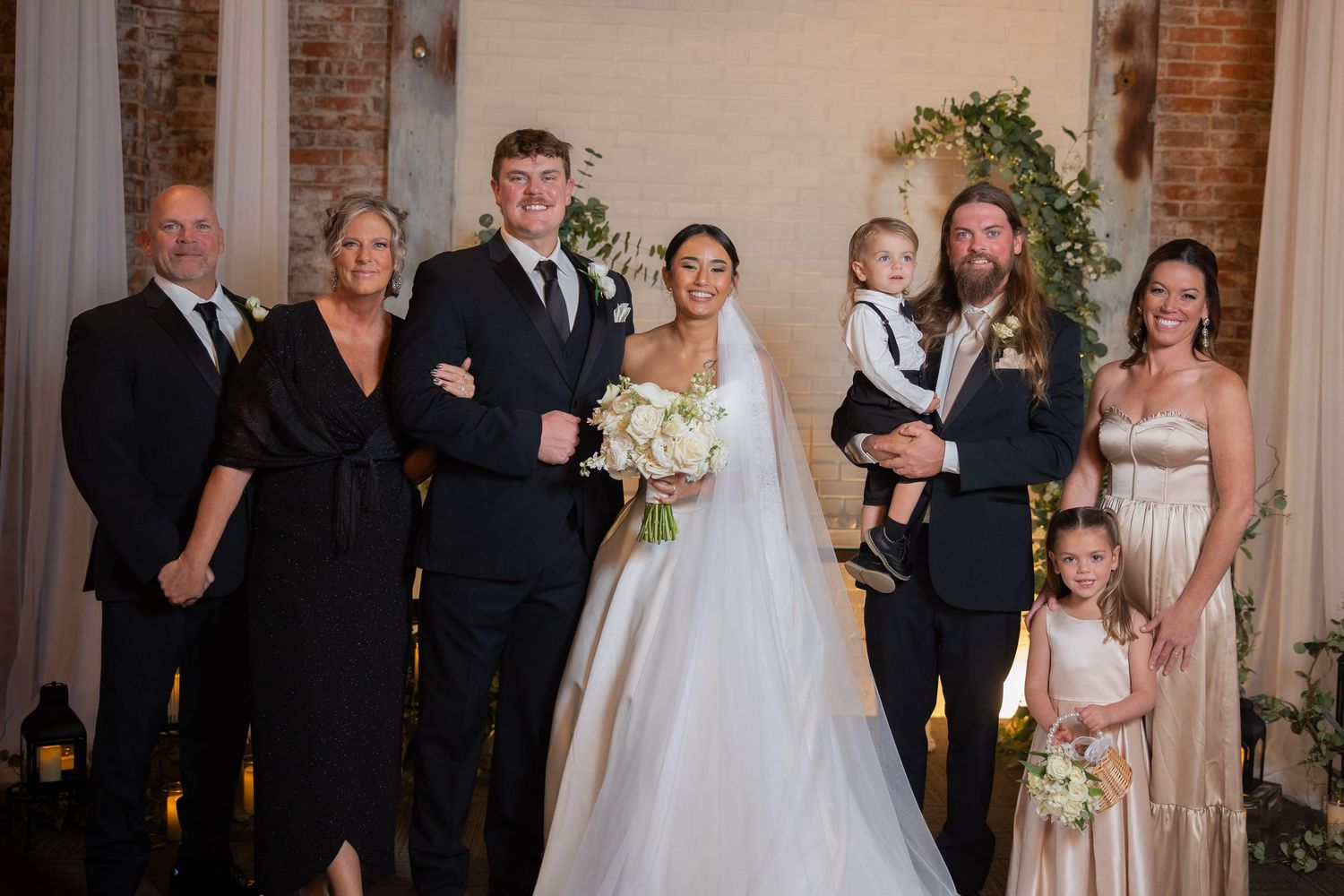 Wedding party and guests gathered in an elegant brick-walled reception venue.