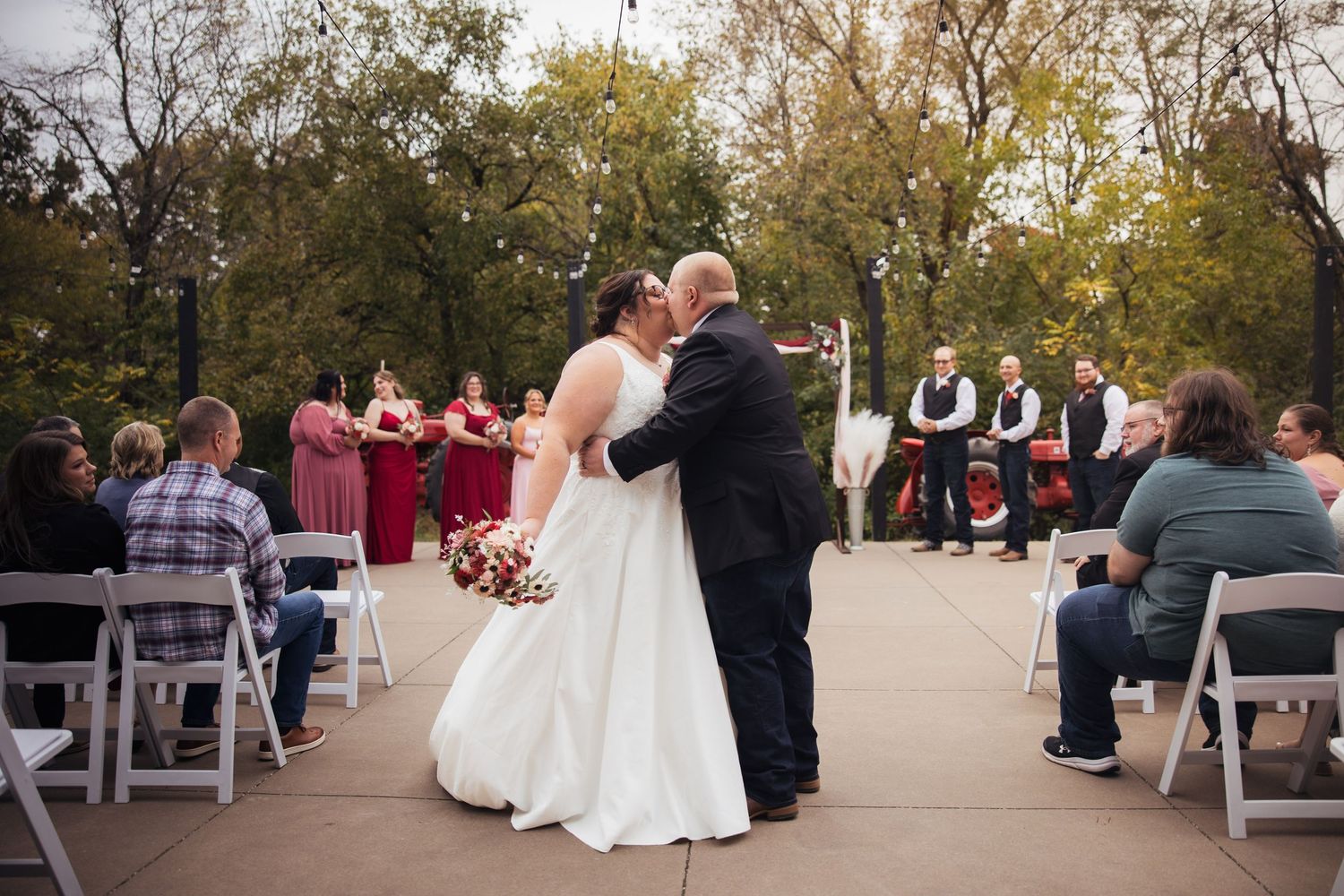 Outdoor wedding ceremony setup with white chairs and autumn trees in the background.