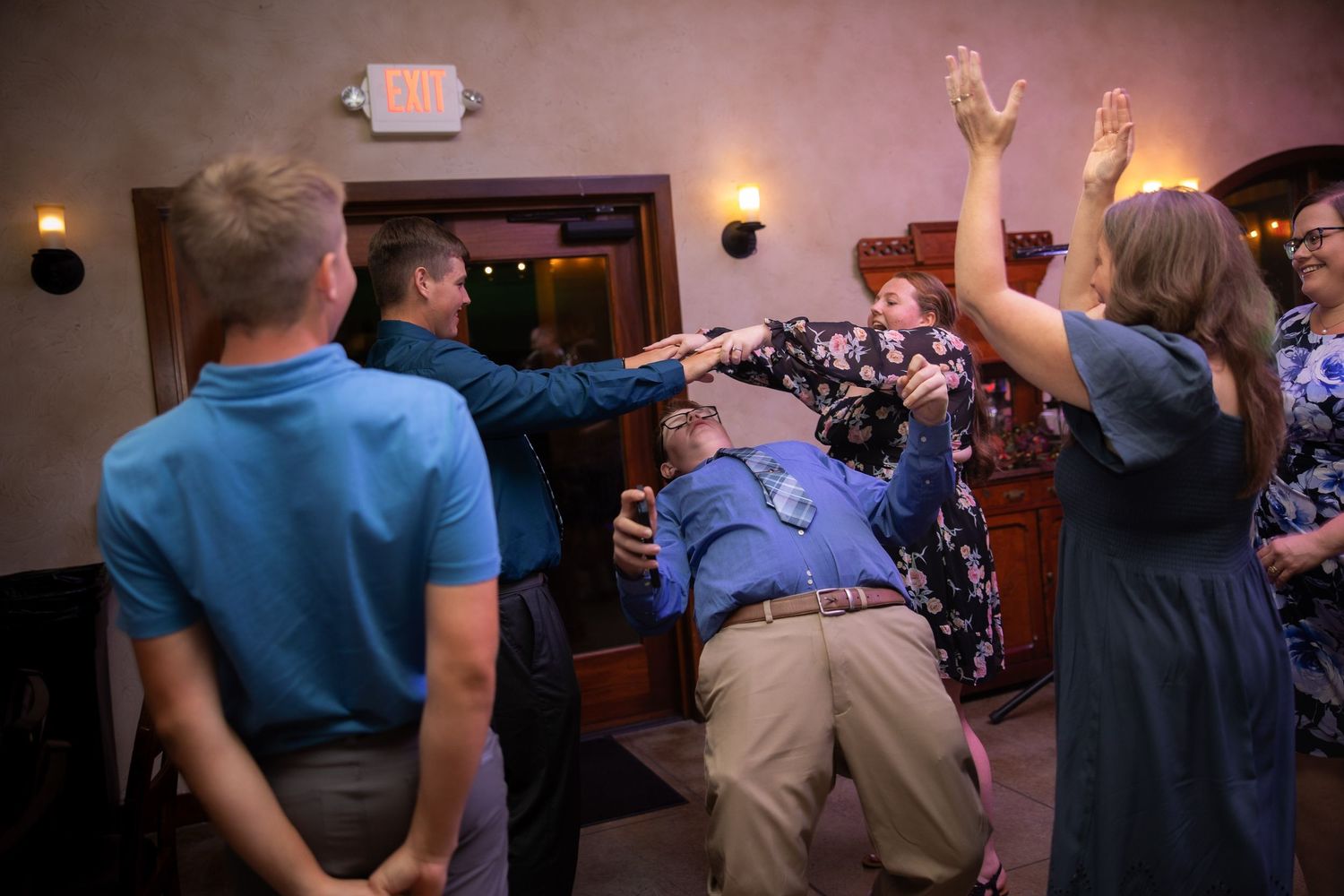 Dancers move across a spacious dance floor under soft pink ambient lighting at an evening social event.