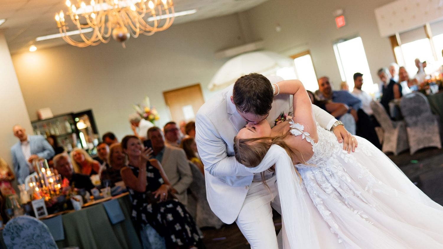 Groom dips bride during romantic first dance at wedding reception.