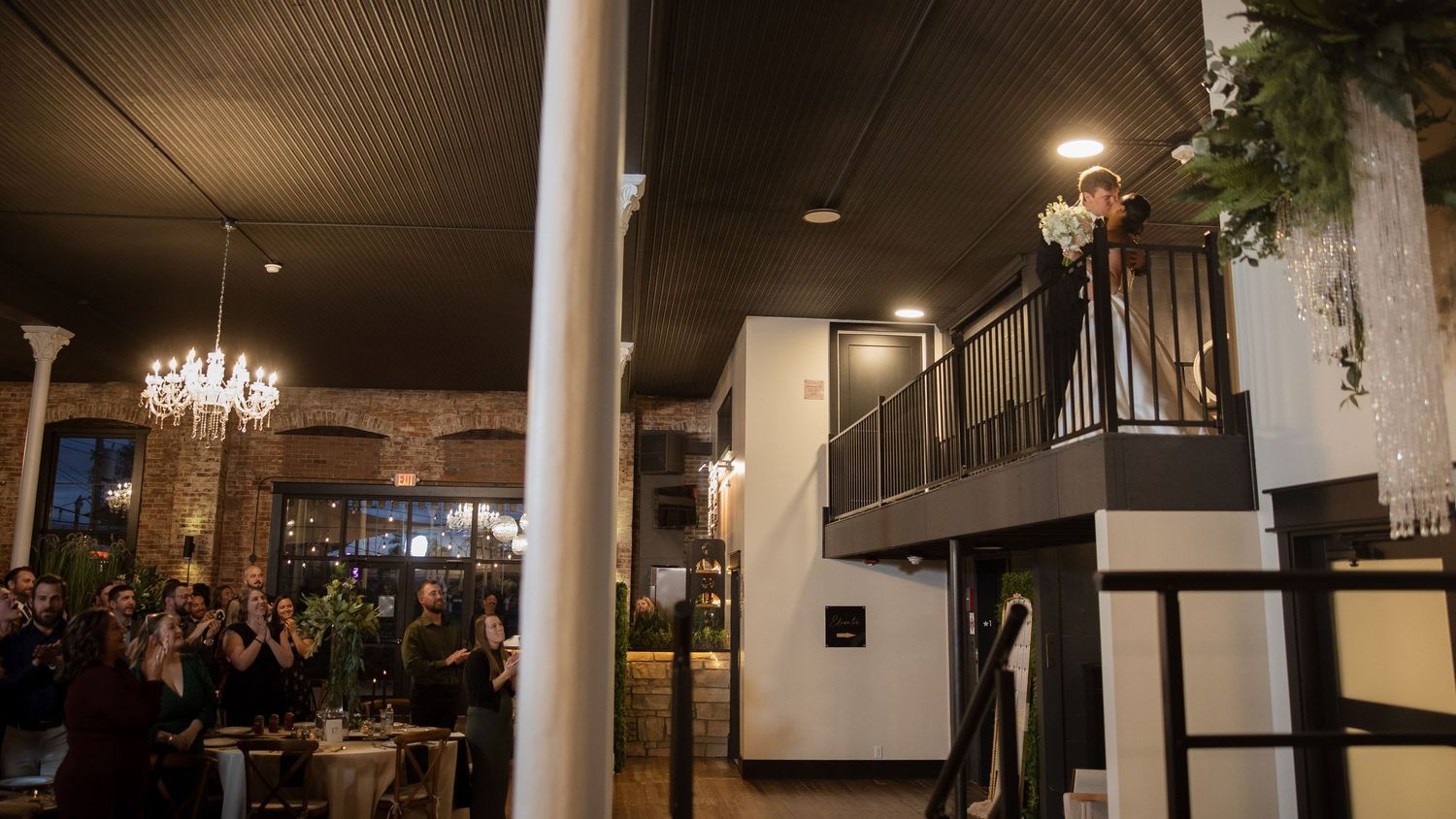 Modern wedding venue interior featuring white columns and exposed brick walls with ambient lighting.