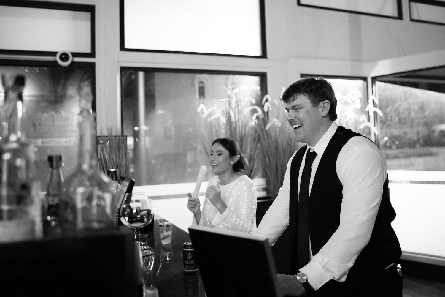 Black and white photo of joyful celebration at wedding bar area.