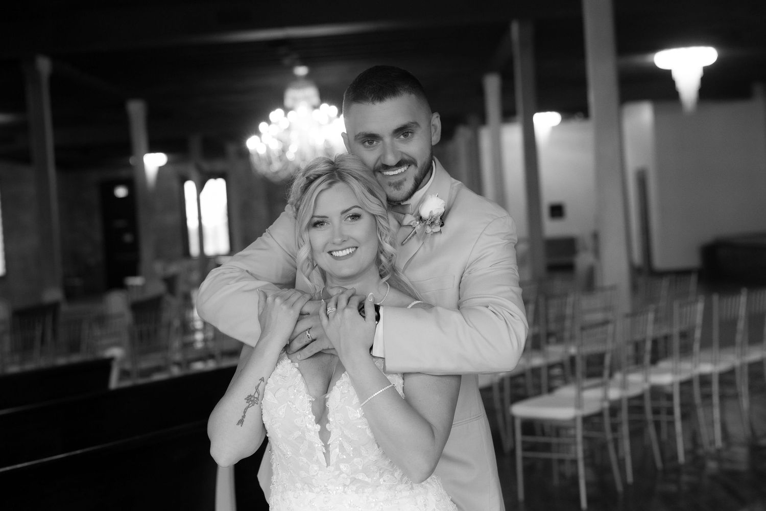 Black and white wedding photo capturing tender moments between newlyweds in elegant venue.
