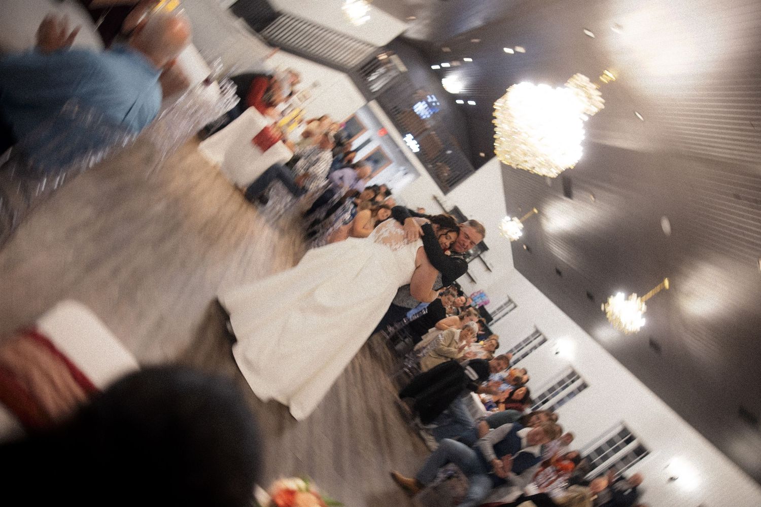 Wedding celebration in an elegant ballroom with crystal chandeliers overhead.
