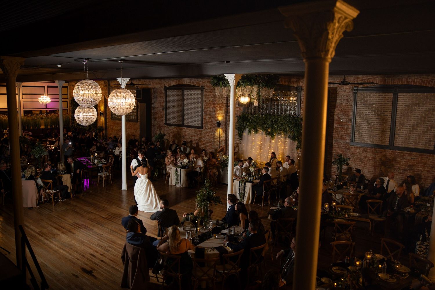 Dark and moody reception venue with hanging lights and exposed brick walls.