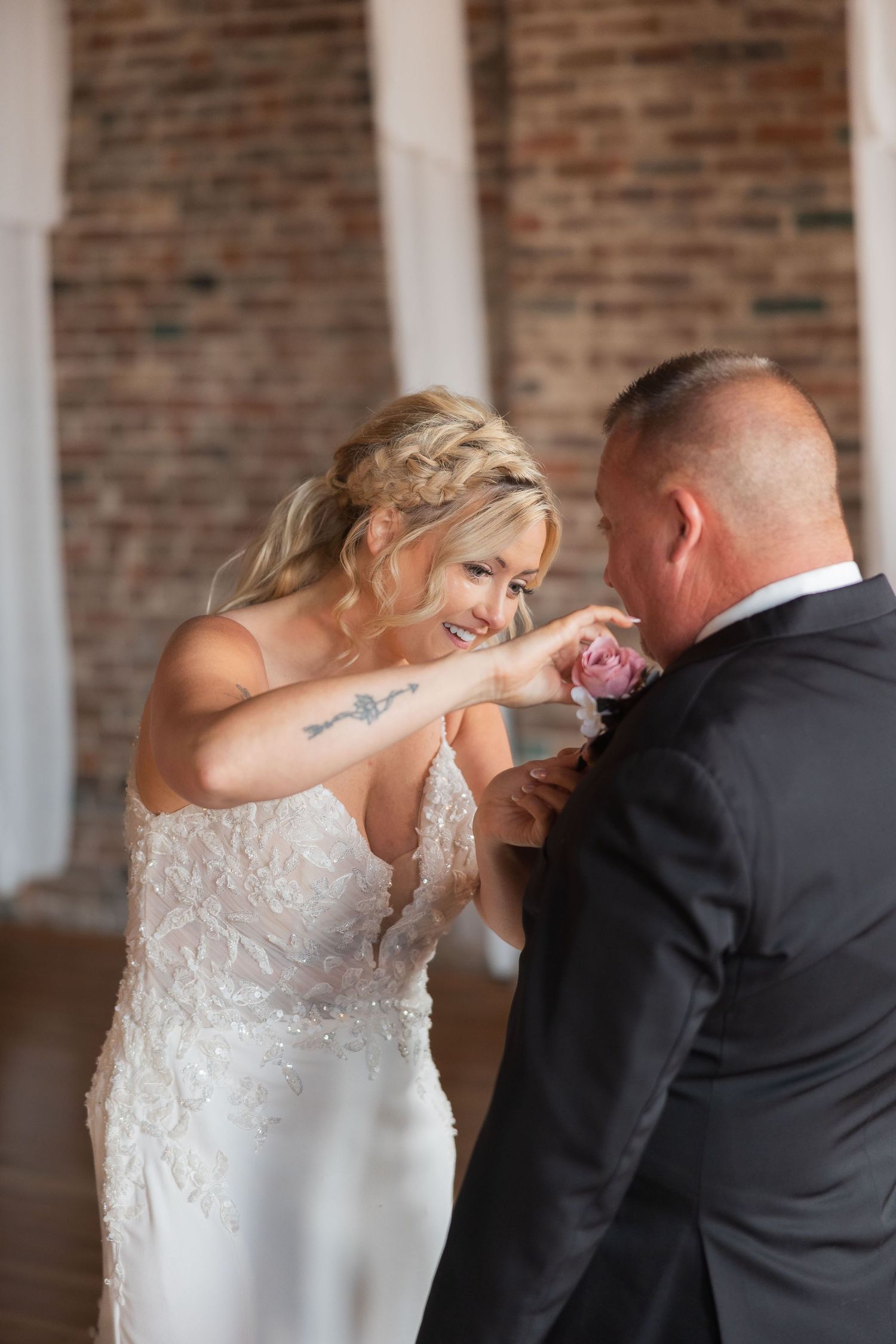 A bride and groom share a playful dancing moment in front of an exposed brick wall.