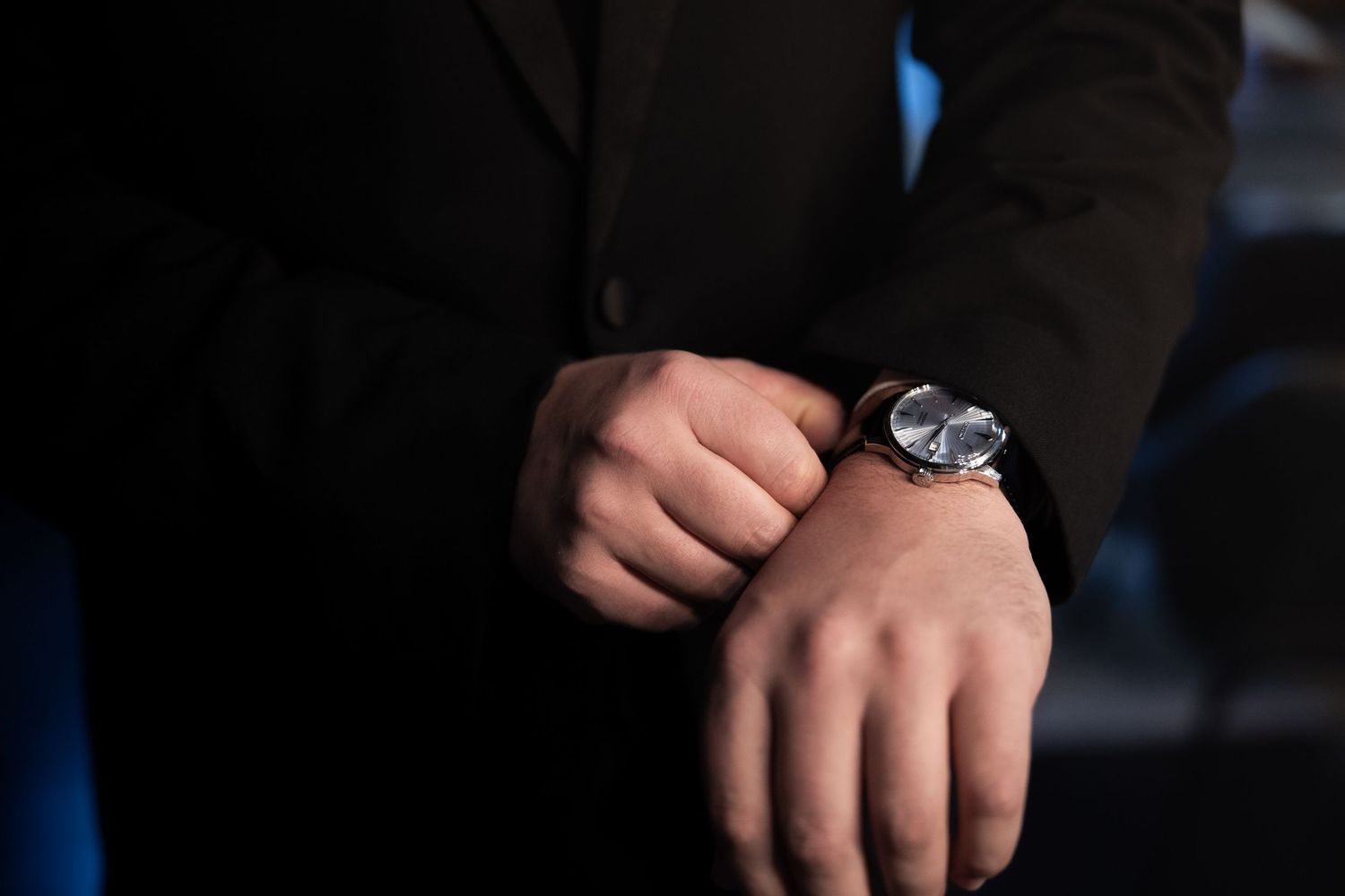 A series of close-up shots showing hands wearing a luxury wristwatch from different angles against a dark background.