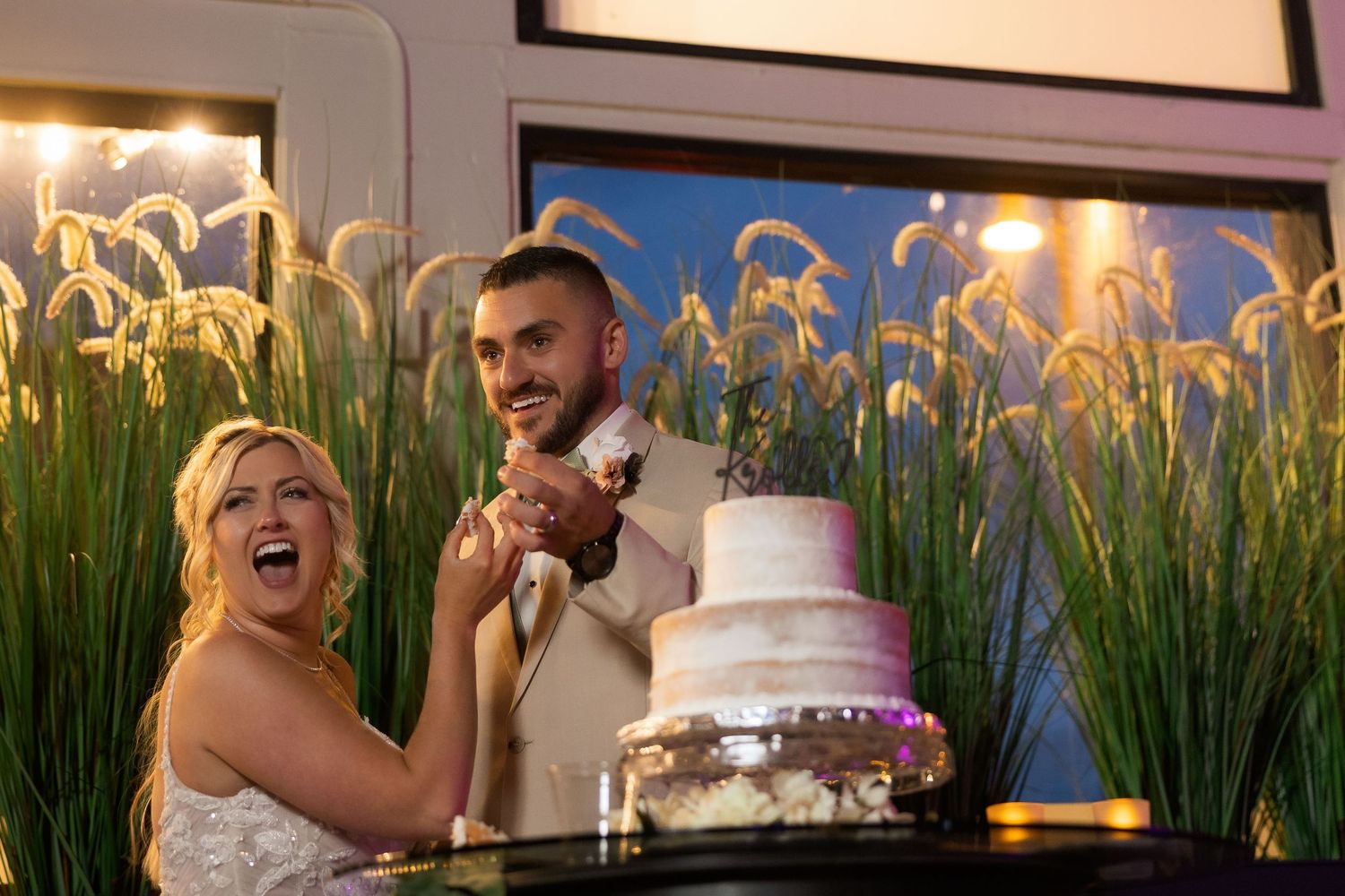Wedding reception celebration with decorative grass wall and festive lighting.