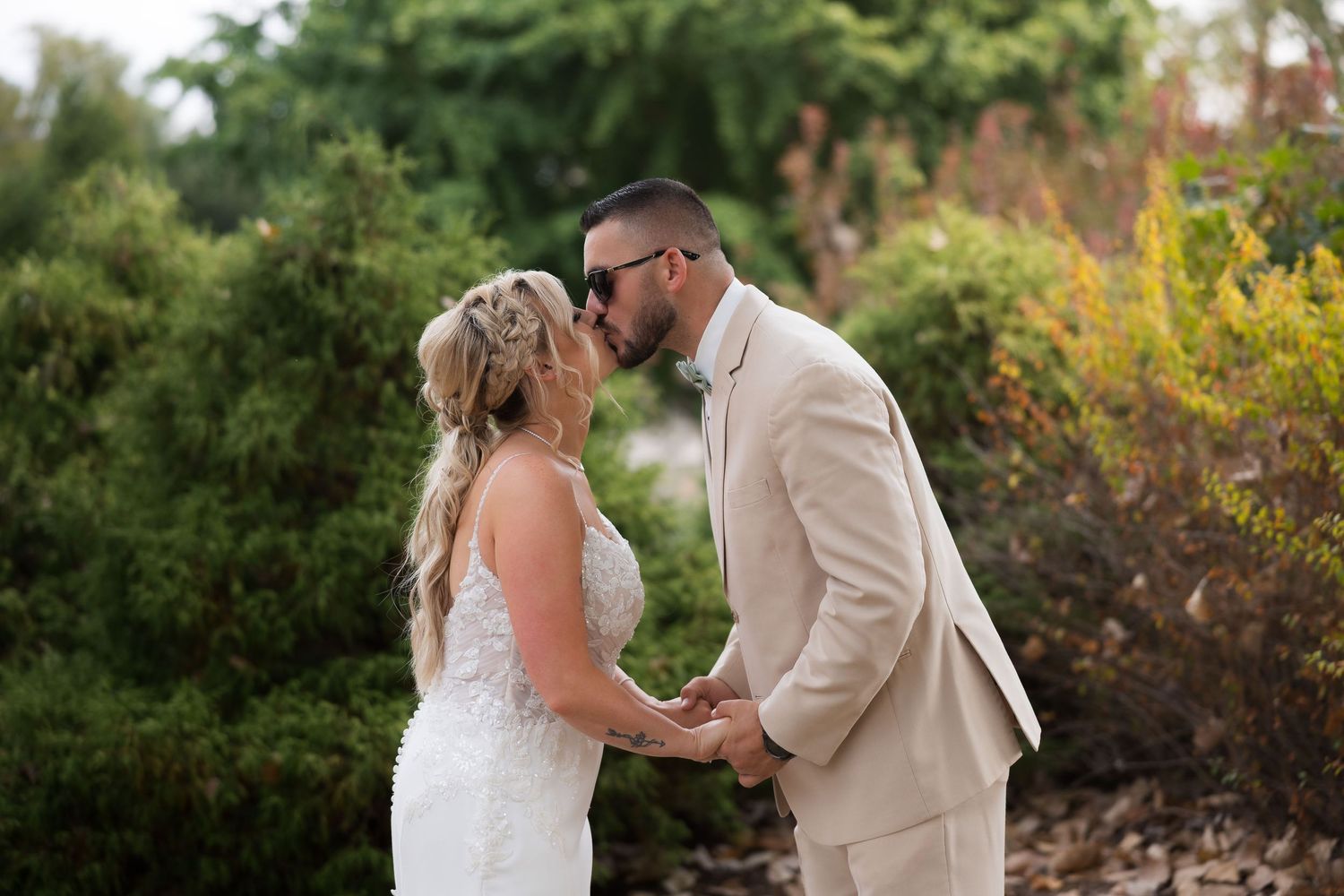 Intimate wedding moment captured in a garden setting with natural greenery.
