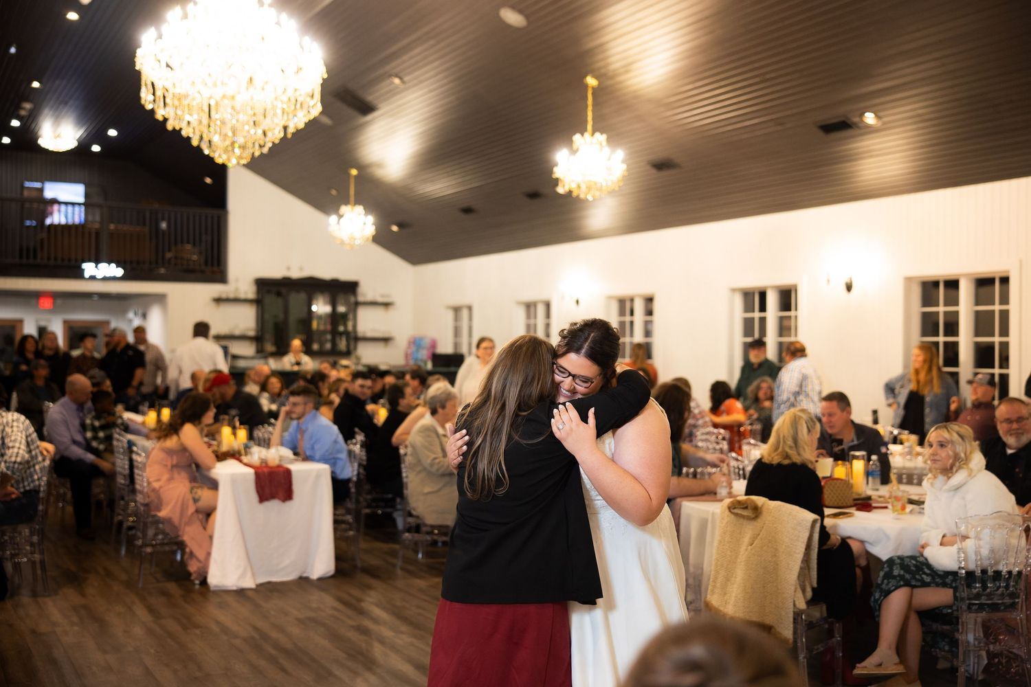 Wedding celebration in a modern venue with crystal chandeliers and hardwood floors during evening festivities.