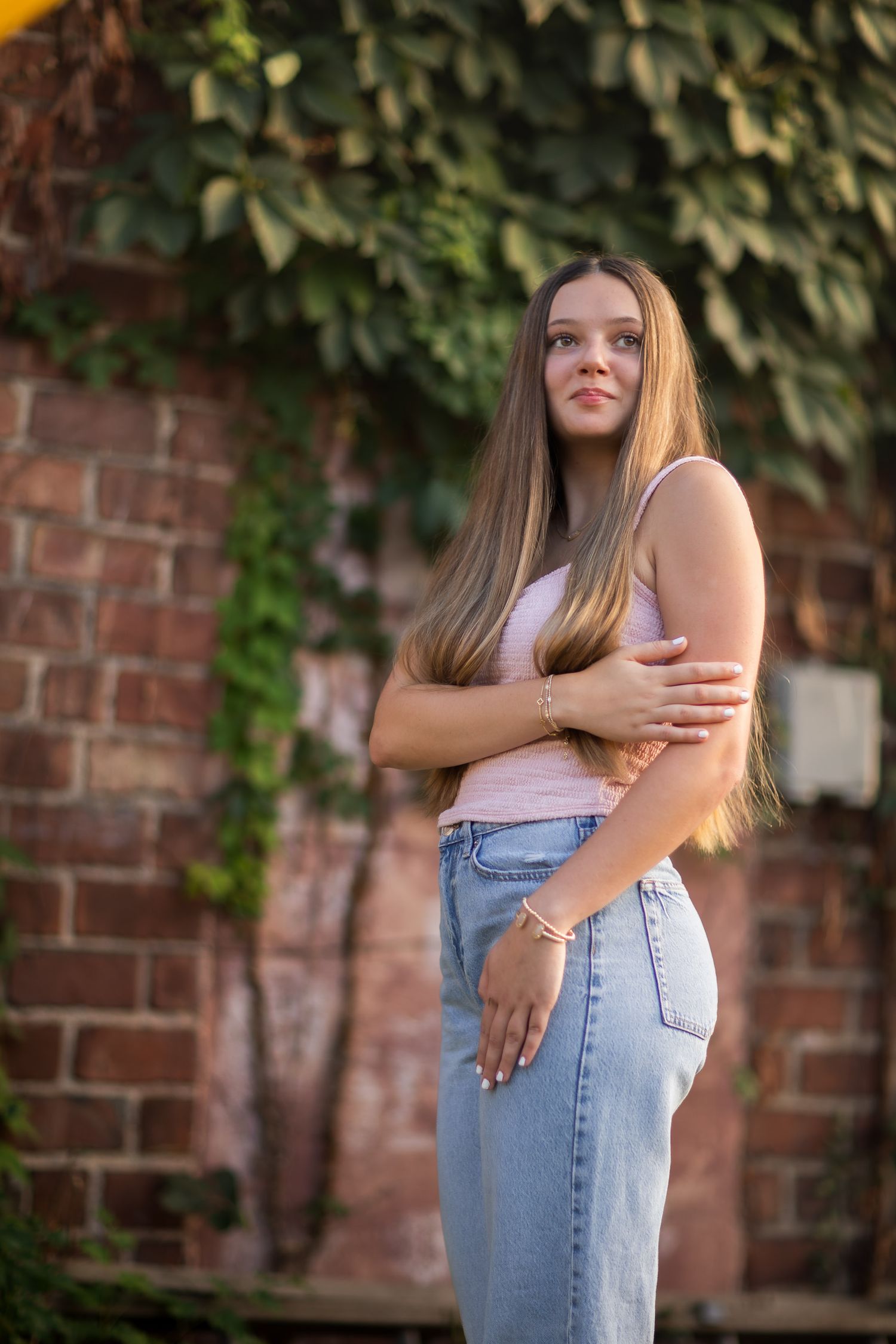Summer portrait session against brick wall with ivy and natural lighting.