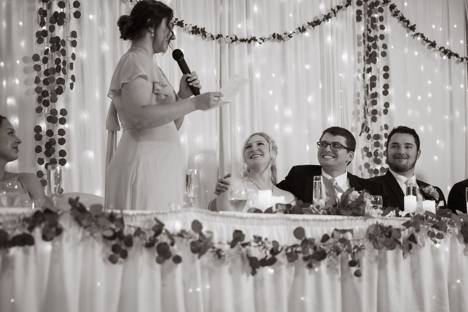 Reception speeches and toasts captured against sparkly backdrop with string lights.
