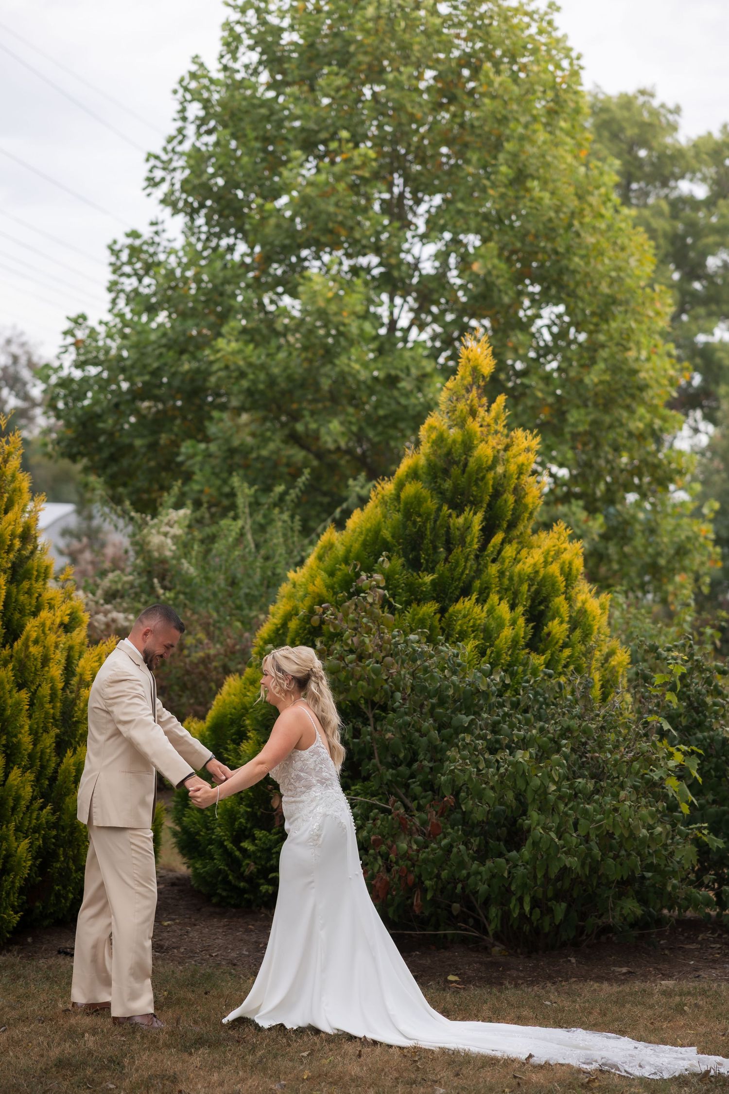 Wedding couple sharing a romantic moment in a garden with yellow flowering shrubs.