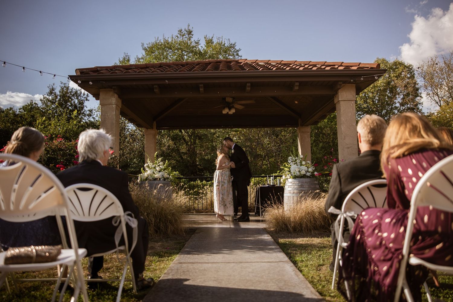 A panoramic view of an outdoor wedding ceremony space with string lights and rustic decor.