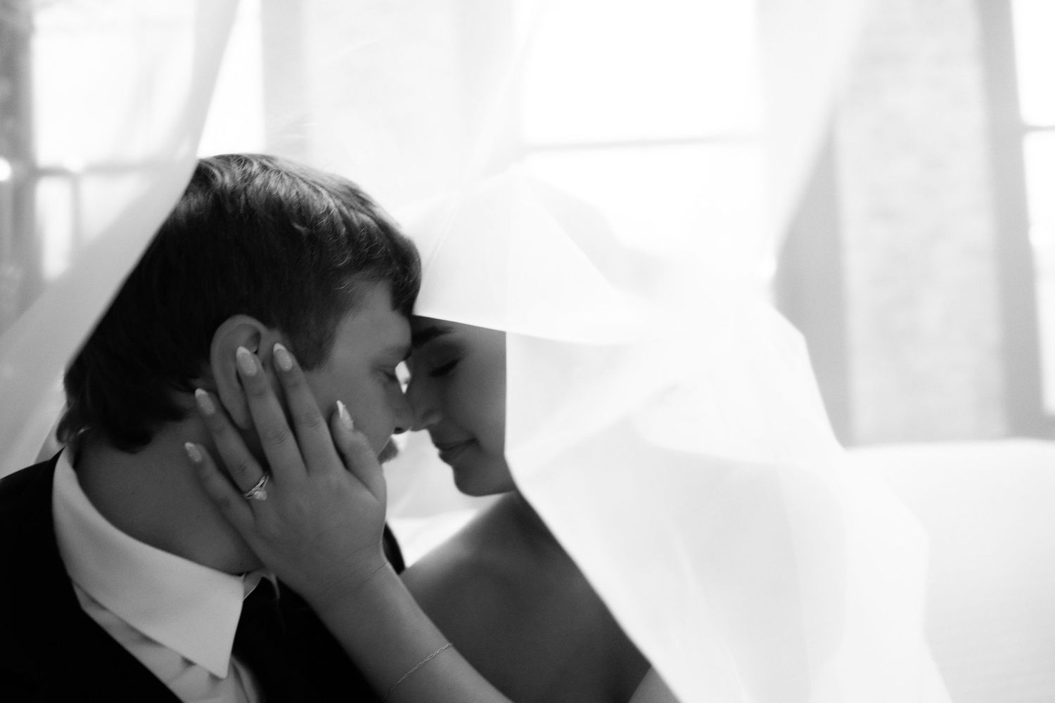 A romantic wedding moment captured against a bright white backdrop in an intimate setting.