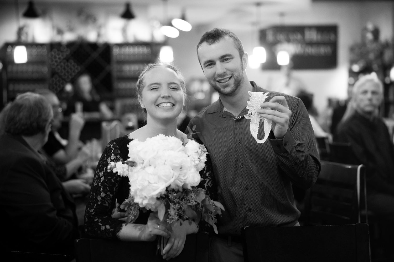 A black and white candid moment of celebration with flowers and joyful expressions.