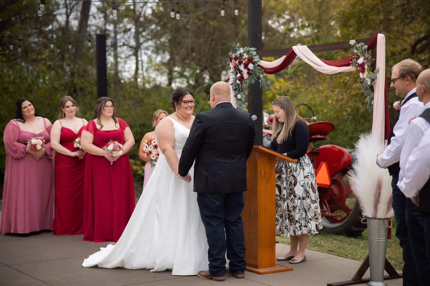 A wedding ceremony takes place outdoors with guests gathered to witness the couple exchange vows.