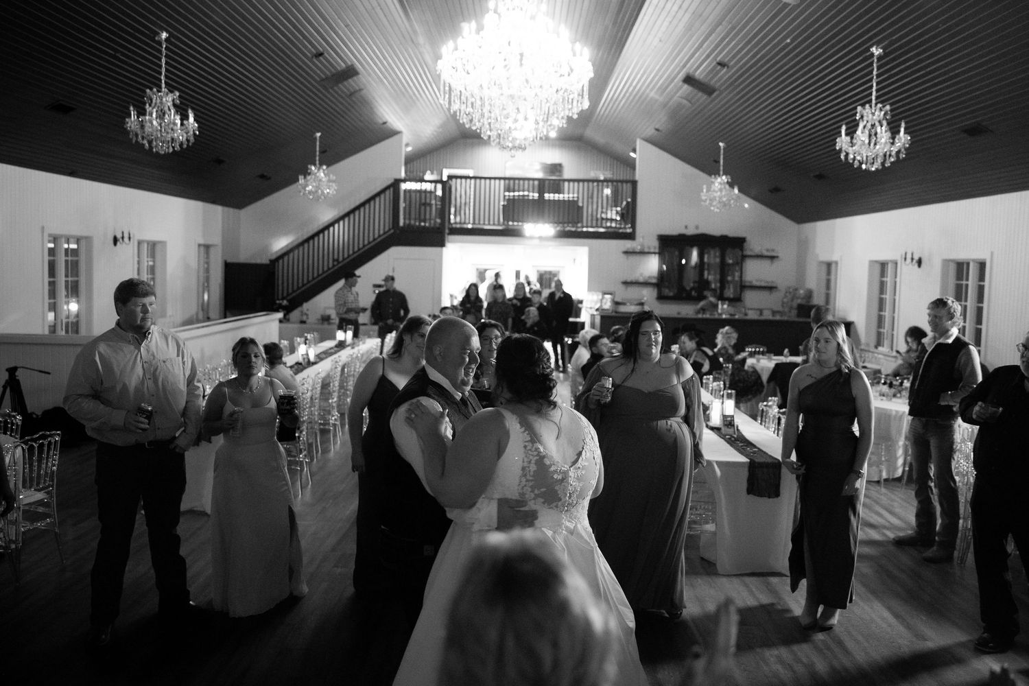 Wedding reception venue with dramatic lighting and chandeliers in black and white.