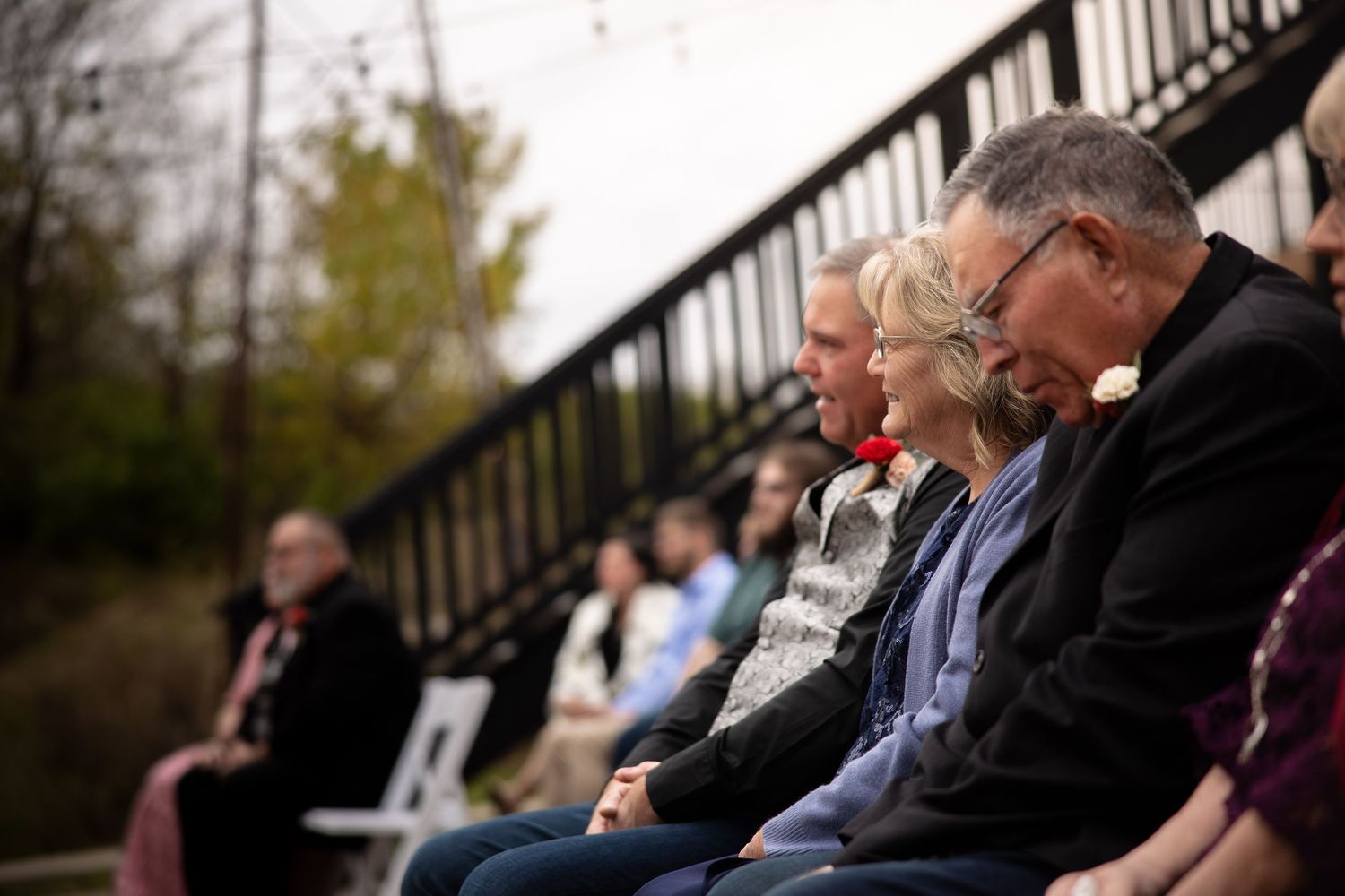 Wedding guests seated on outdoor benches watching the ceremony.