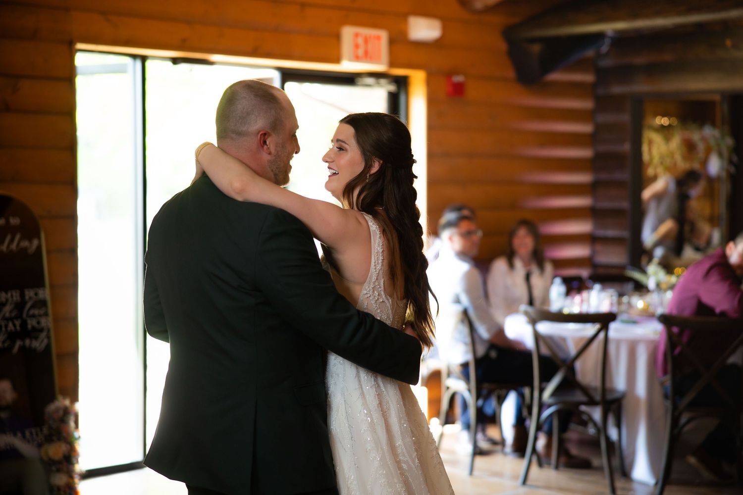 Bride and father share emotional first dance in rustic log cabin wedding reception venue.